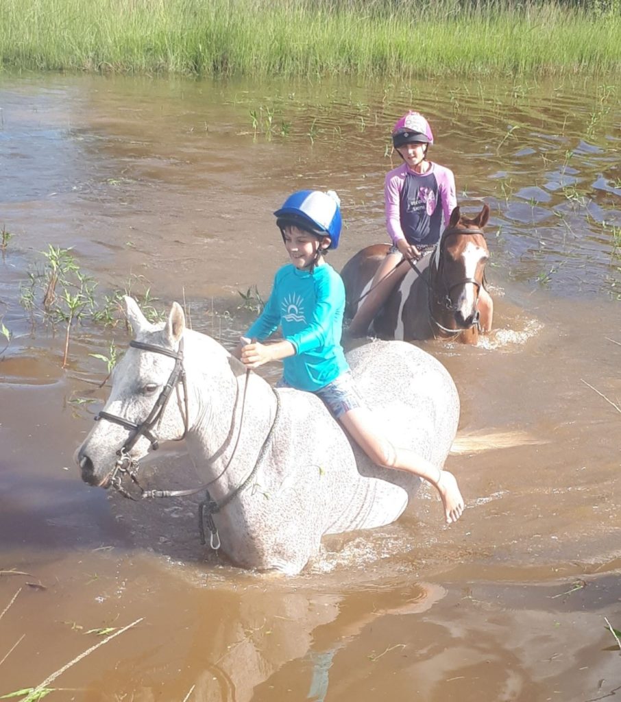 kids swimming their ponies in the dam. 